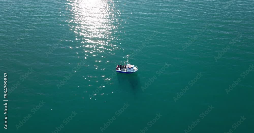 Unrecognizable fishermen fishing on board of boat in Lyngen fjord on sunny day, Norway. Aerial top-down orbiting overhead Unrecognizable fishermen fishing on board of boat in Lyngen fjord on sunny day, Norway. Aerial top-down orbiting overhead