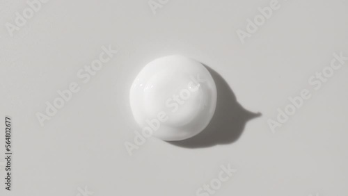 Eye care cream advertisement | Top view macro shot of white eye care cream drop appears from the shadow on white background