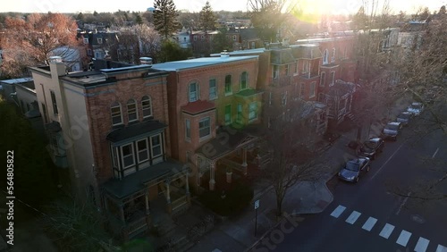 Slow aerial approach towards historic brick houses in American city. Bright golden hour light on dark homes in urban USA during winter. photo