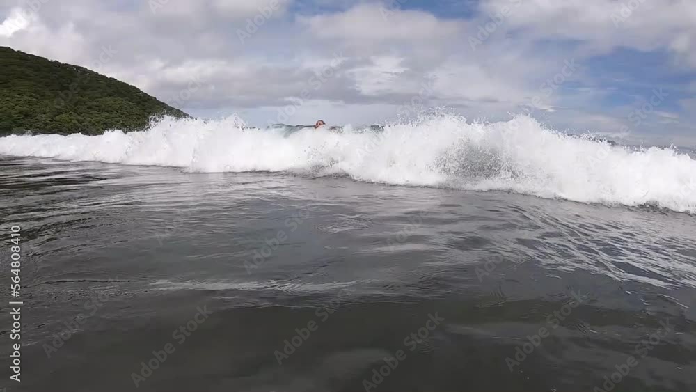Girl swimming in slow motion on top of a wave on a beach in Costa Rica Girl swimming in slow motion on top of a wave on a beach in Costa Rica