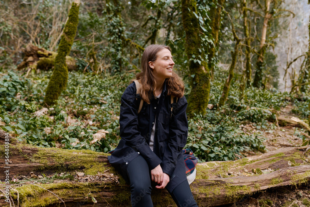 young woman travels through an old dead forest with a backpack young woman travels through an old dead forest with a backpack