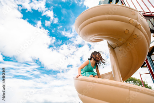 A girl slides down a spiral slide