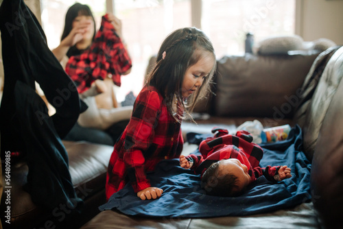 adorable toddler admiring her newborn baby brother lying on the couch photo