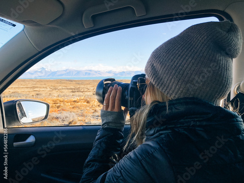 Woman tourist photographing scenery from her car