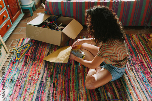 Young woman packing used clothes for sell photo