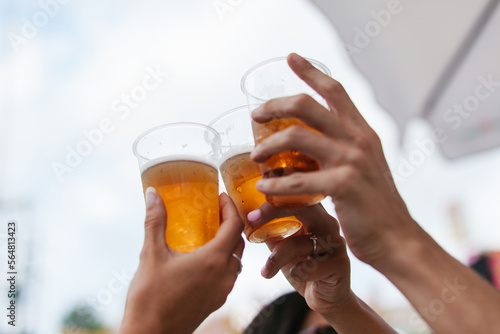 Crop anonymous friends toasting with beer in cafe photo