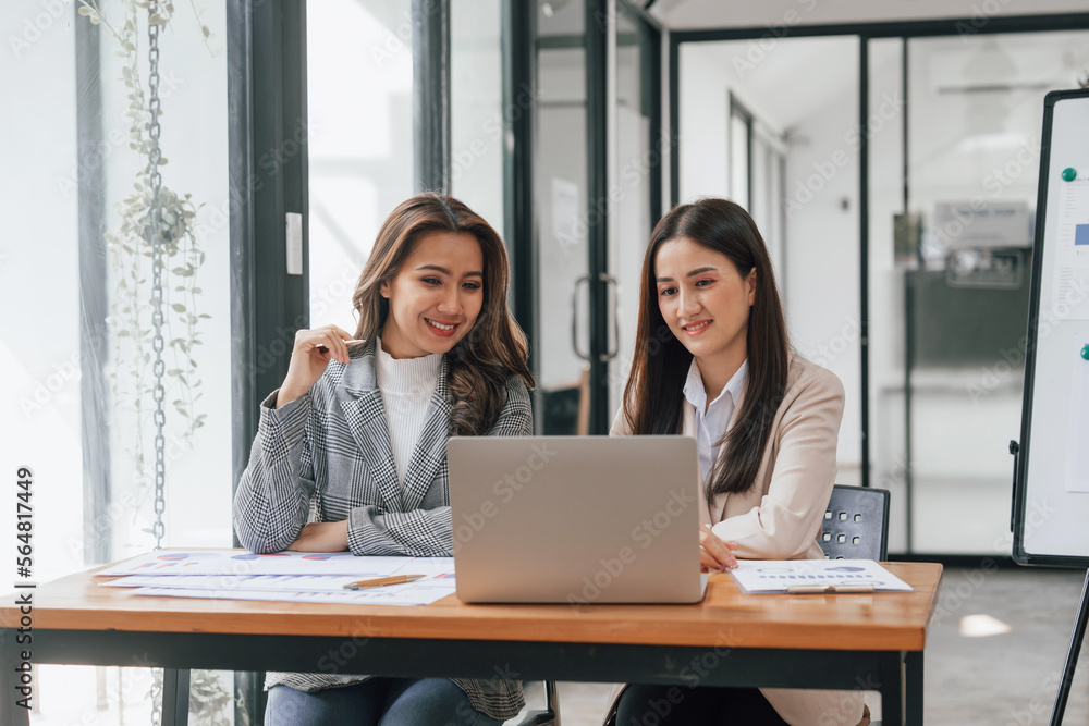 Two young pretty asia business woman in suit talking together in modern office workplace, Thai woman, southeast asian Two young pretty asia business woman in suit talking together in modern office workplace, Thai woman, southeast asian