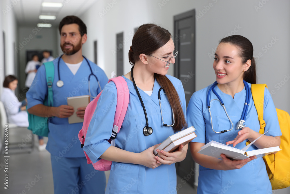Smart medical students with books in college hallway, space for text Smart medical students with books in college hallway, space for text