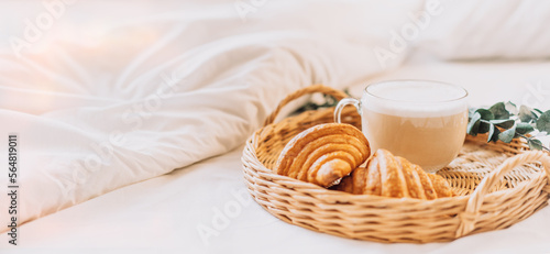 Tray with croissants on white bed linen.