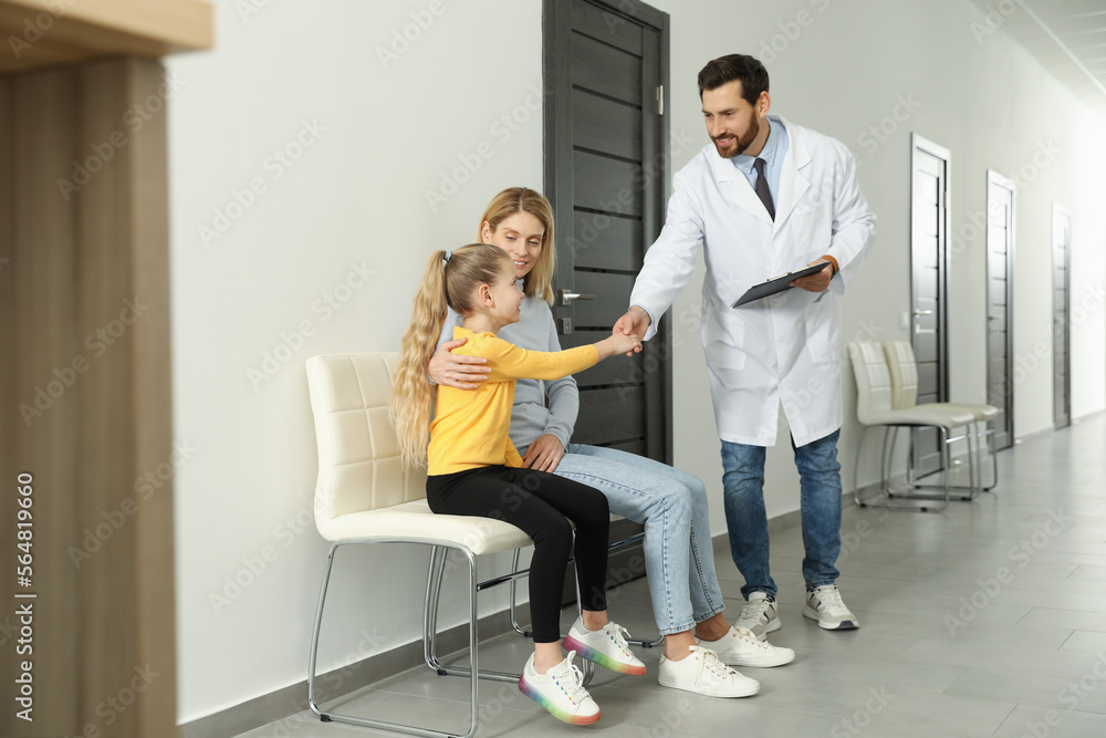 Mother and daughter having appointment with doctor. Pediatrician shaking hands with patient in clinic Mother and daughter having appointment with doctor. Pediatrician shaking hands with patient in clinic