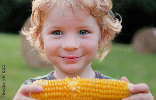 Obraz na płótnie Young caucasian 4-year old child with curly hair eats corn off of the cob and sm