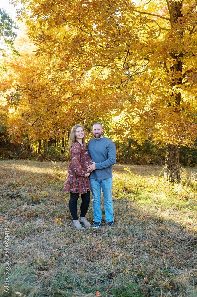 man and pregnant woman hugging outdoors in fall man and pregnant woman hugging outdoors in fall