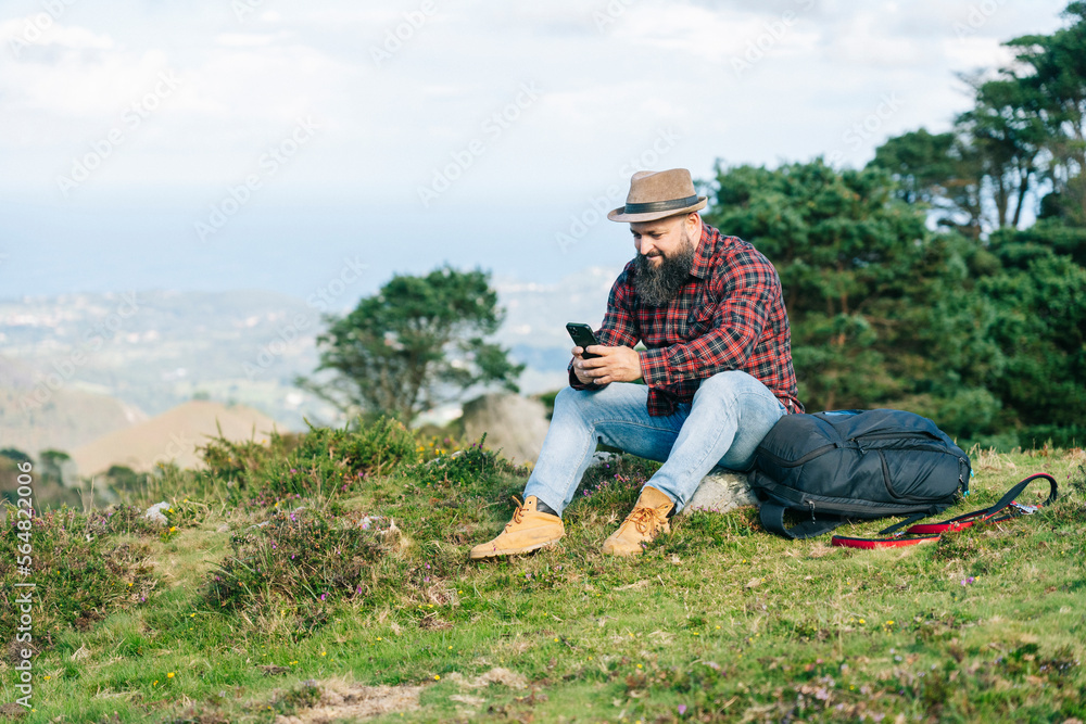 Male hiker using smartphone on grassy hill Male hiker using smartphone on grassy hill