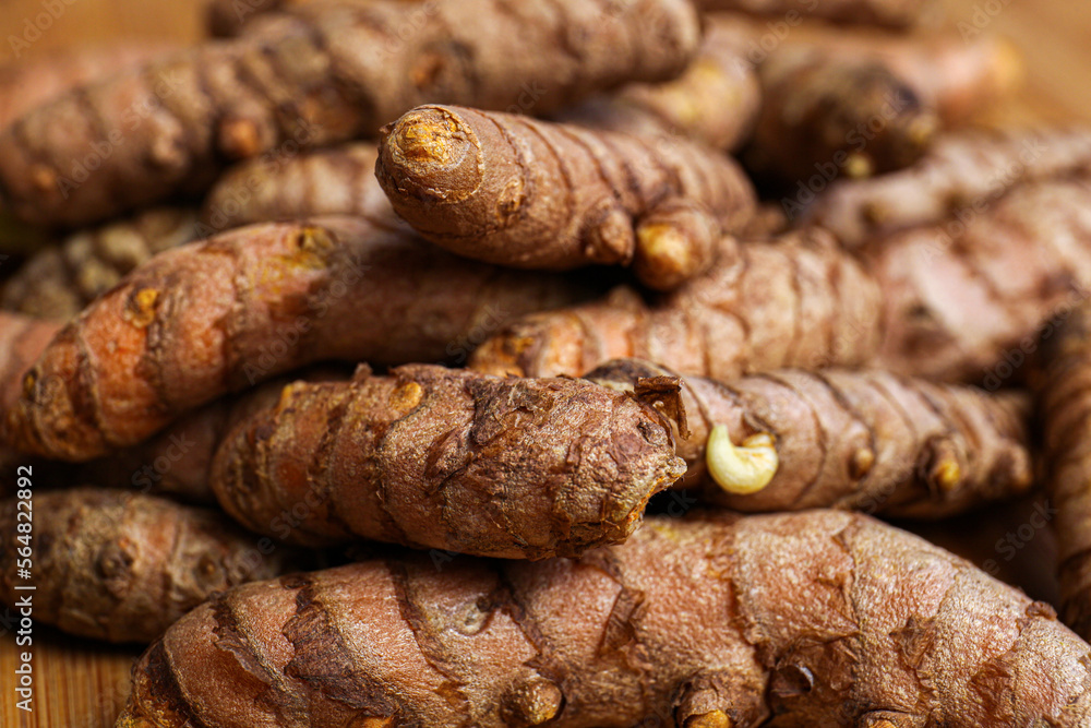 Many whole turmeric roots on wooden table, closeup Many whole turmeric roots on wooden table, closeup