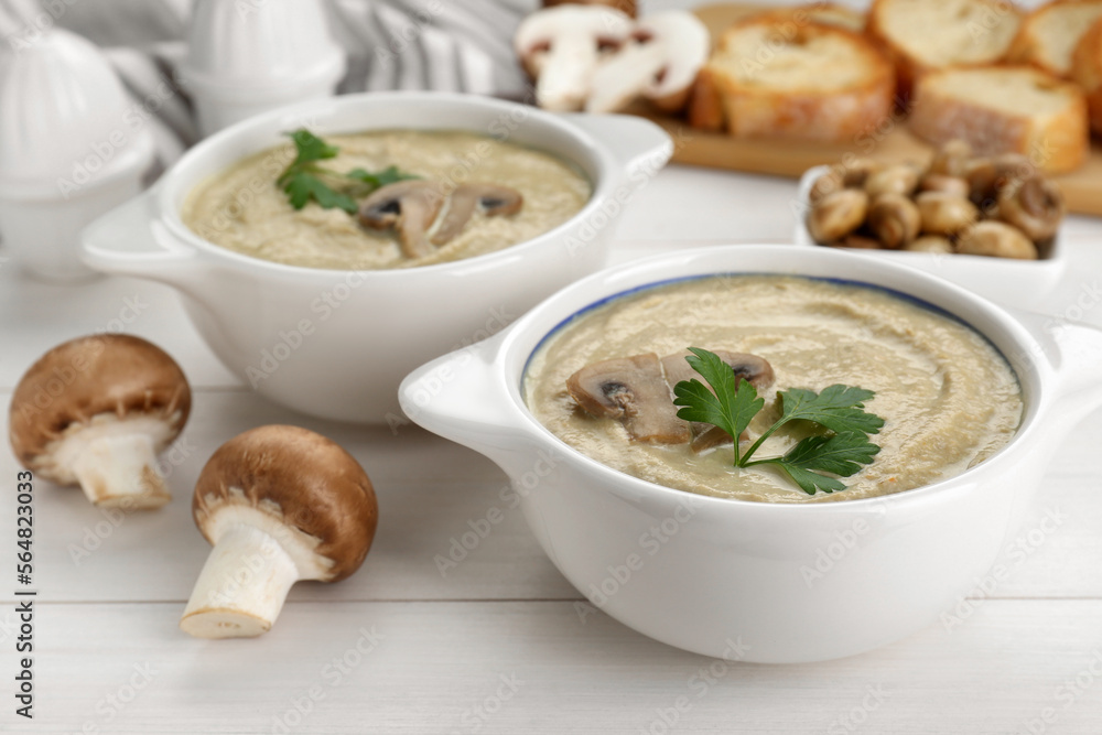 Delicious mushroom cream soup with parsley on white wooden table Delicious mushroom cream soup with parsley on white wooden table