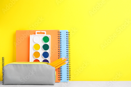 Different school stationery on white table against yellow background, space for text. Back to school
