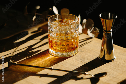 whiskey drink on a wooden table with a barspoon and a jigger 