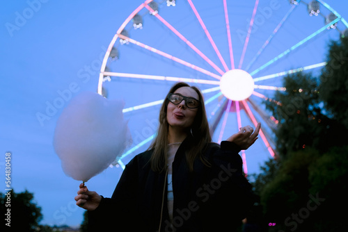 portrait of a pretty young girl eating cotton candy at amusement park photo