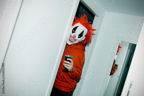 man wearing a clown mask holds a glass photo