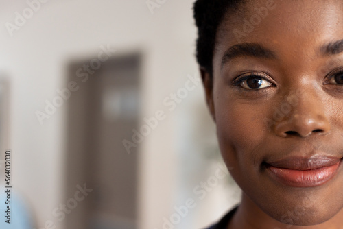 Half face portrait of smiling african american female doctor in hospital corridor with copy space photo