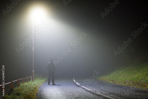 A man stadning under a street light photo