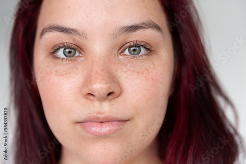 Close-up portrait of a young woman with calm-looking green eyes