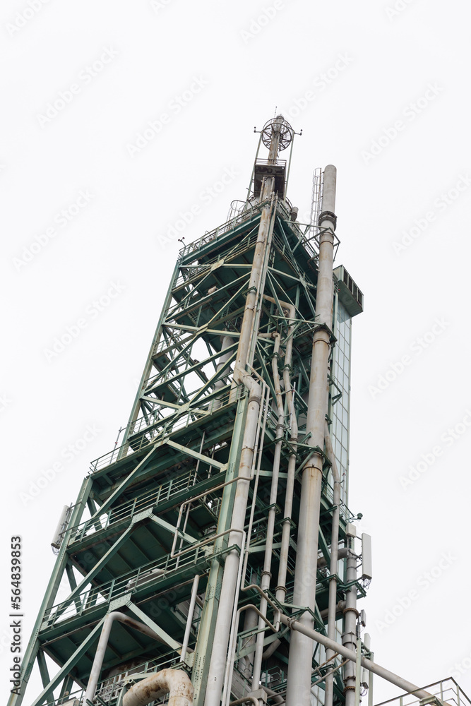 Obraz premium High oil and gas processing tower on a background of grey sky