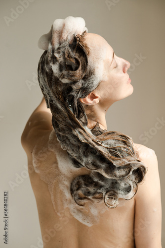 Beautiful young woman with her back with soapy hair