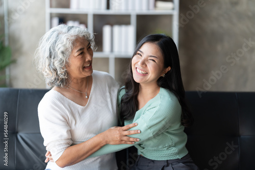 Loving grown up daughter. hugging middle aged mother in living room.