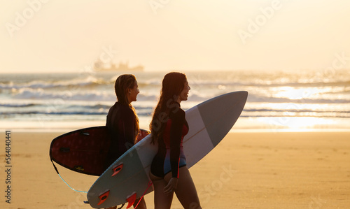 Happy surfers against sunset sky and waving sea photo