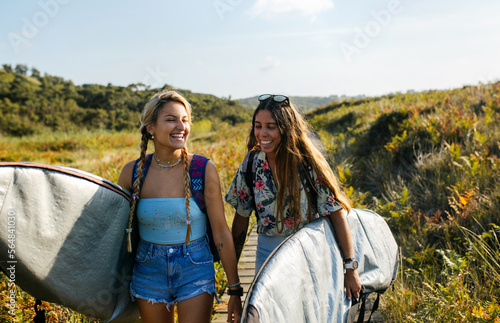 Excited female surfers walking on boardwalk photo