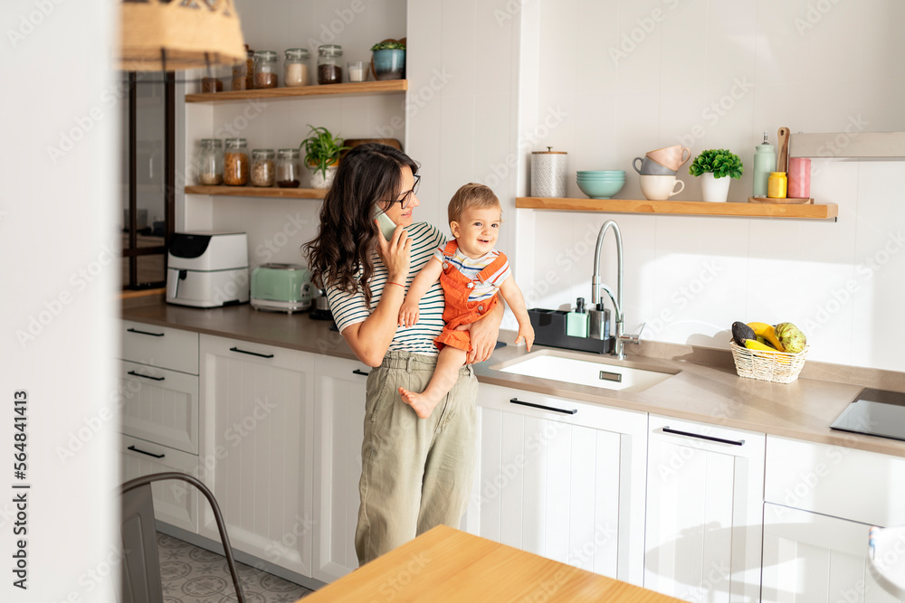Mother having a conversation and holding her son Mother having a conversation and holding her son