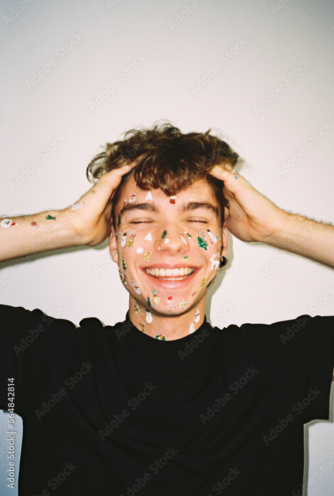 © BONNINSTUDIO/Stocksy - User-generated content young man with Christmas stickers smiling © BONNINSTUDIO/Stocksy - User-generated content young man with Christmas stickers smiling