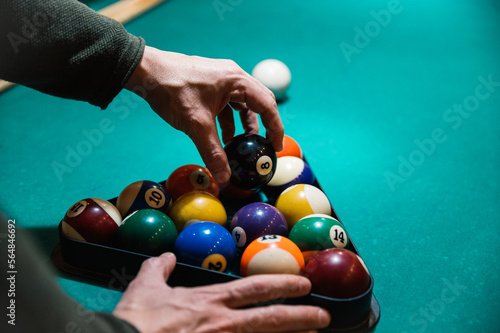Crop man arranging balls in rack on billiard table photo