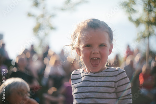 Girl smiles and laughs at outdoor theater in afternoon sunshine photo