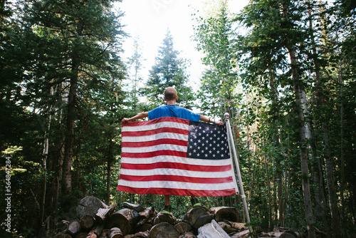 American flag held by boy in pristine pine tree forest in America