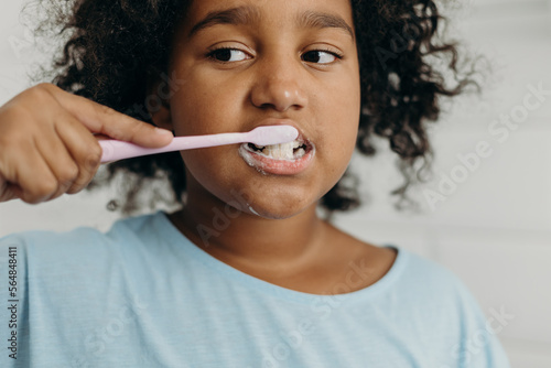 Mixed raced girl brushing teeth photo