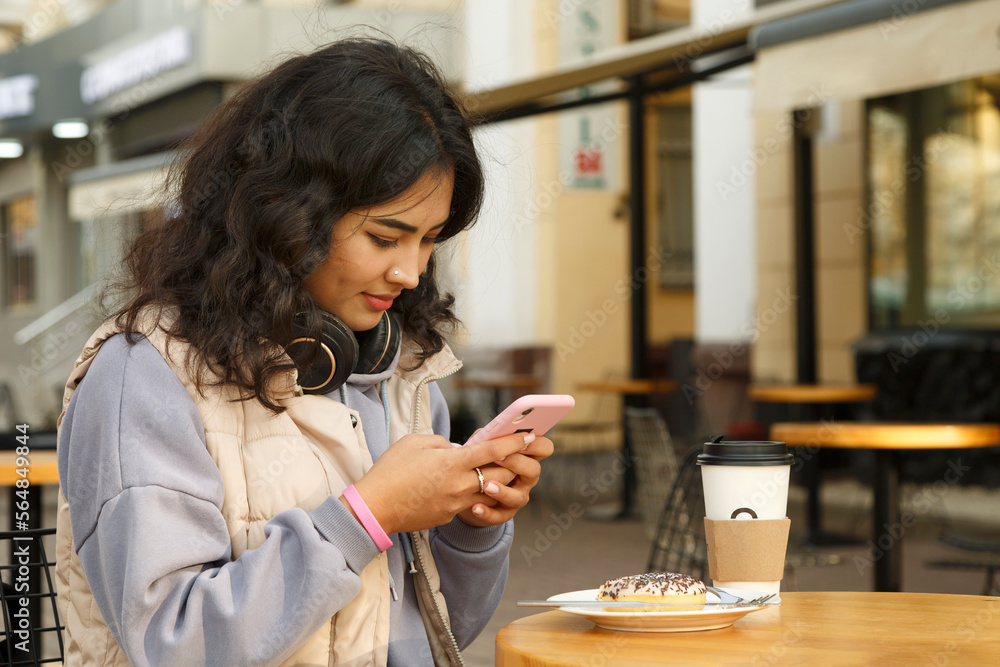 Young woman browsing smartphone in street cafeteria Young woman browsing smartphone in street cafeteria