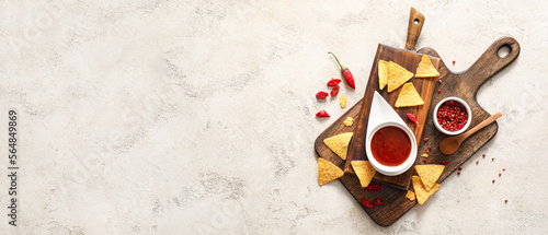 Composition with tasty nachos, sauce and spices on light background with space for text, top view