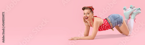 Young pin-up woman in roller skates on pink background with space for text photo