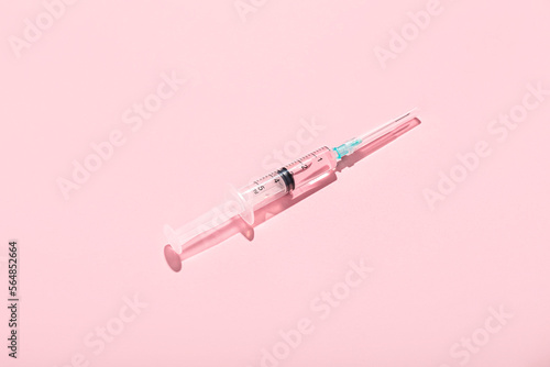 Medical syringe with remedy on pink background photo