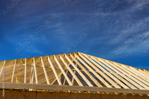 Using an frame of trusses framework, stick wooden roof beam install it on newly built home