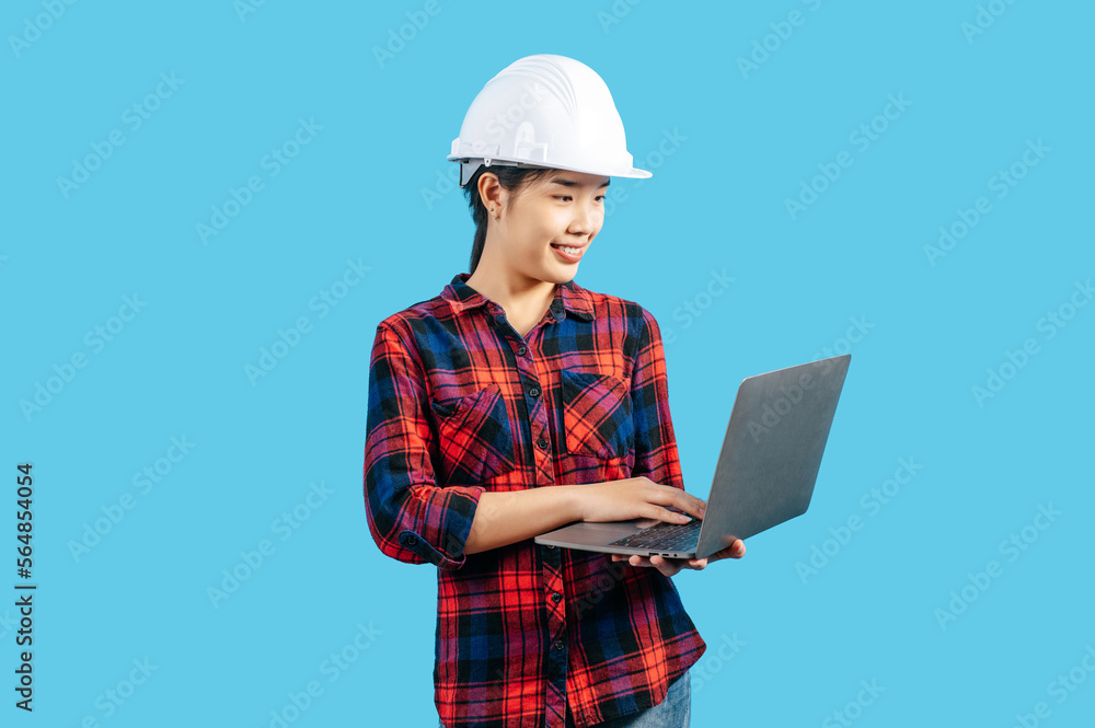 Young female engineer wearing helmet and use laptop computer
