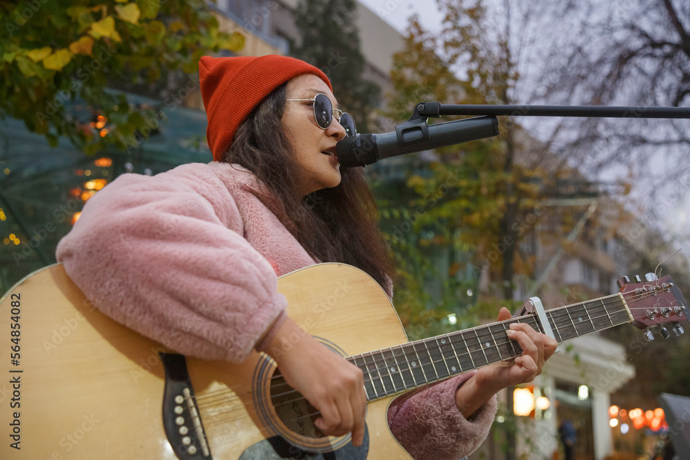 © Danil Nevsky/Stocksy - Asian female singer performing live concert on street