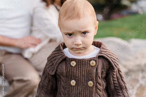 A brown-eyed caucasian baby boy kid toddler in a brown knitted s photo