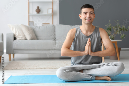 Young man meditating on mat...