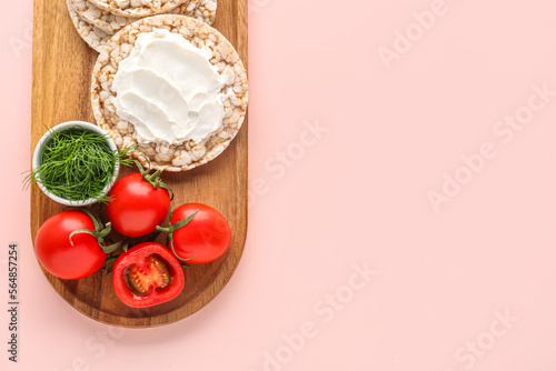 Wooden board of crispbreads with cream cheese, tomatoes and dill on pink background photo