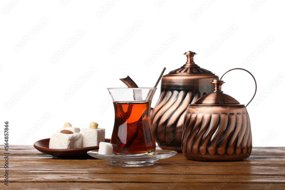 Fototapeta premium Cup of Turkish tea, teapot, sugar bowl and sweets on wooden table against white background