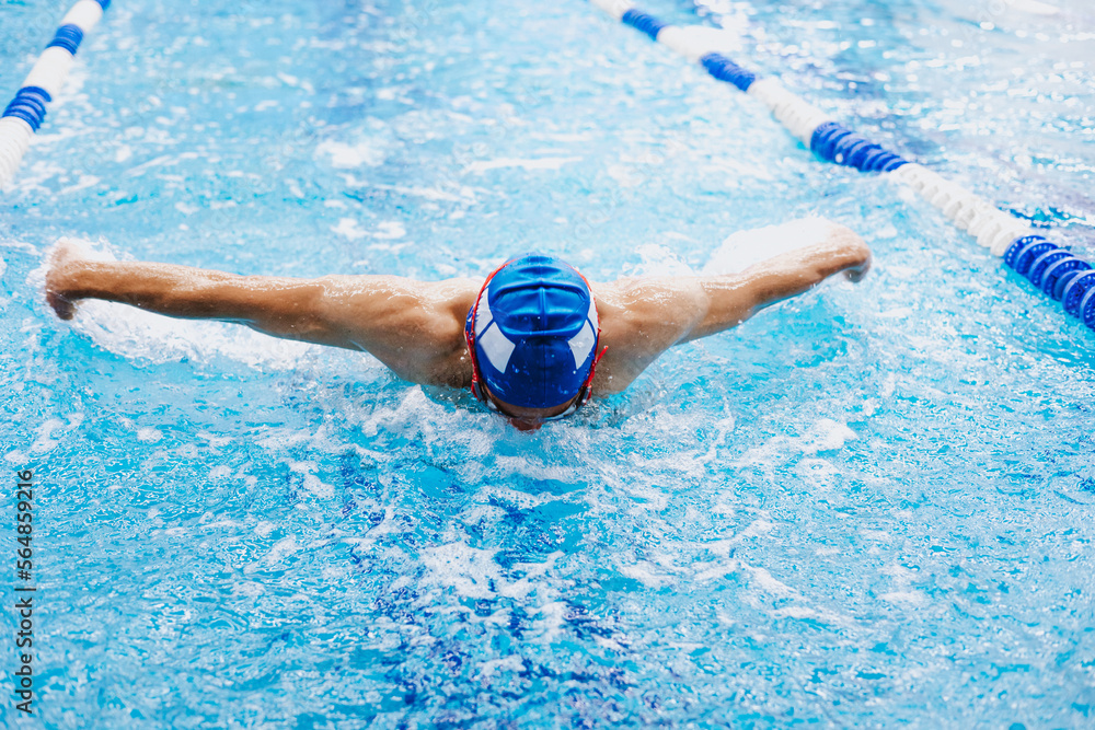 hispanic young man swimmer athlete wearing cap and goggles in a swimming training at the Pool in Mexico Latin America	