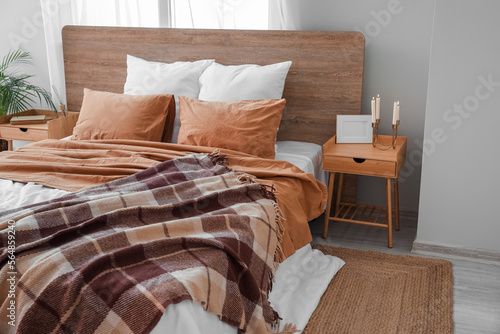 Big bed with wooden tables in interior of bedroom